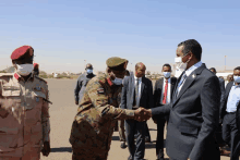 a man wearing a mask shakes hands with a military officer