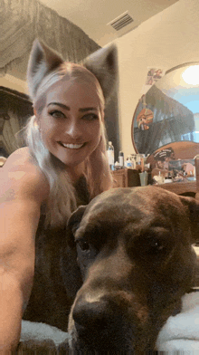 a woman wearing a cat ear headband smiles next to a large dog