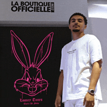 a man wearing a looney tunes shirt stands in front of a sign