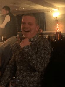 a man in a floral shirt is smiling while sitting in a dark room