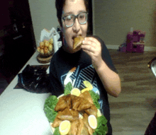 a person wearing glasses is eating food from a plate with lemons and lettuce