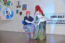 two women dancing in front of a sign that says 1995- 2017