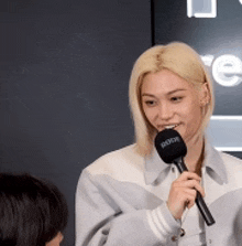 a woman is holding a microphone in her hand and smiling while talking to another woman .