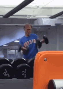 a man in a blue shirt with the word russia on it lifts a dumbbell