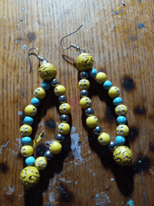 a pair of yellow and turquoise beaded earrings on a wooden surface