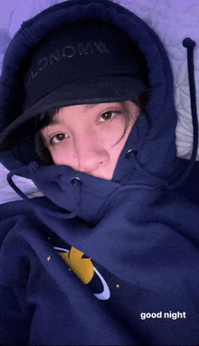 a woman wearing a black hat and a blue hoodie with the words good night below her