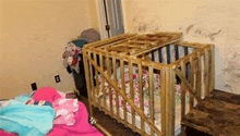 a wooden crib is sitting on a wooden floor in a room .