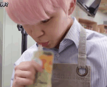 a young man with pink hair is drinking from a bottle