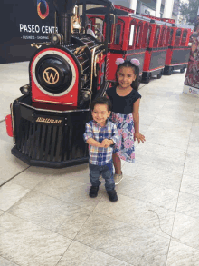 two children stand in front of a train that says walkman on the front