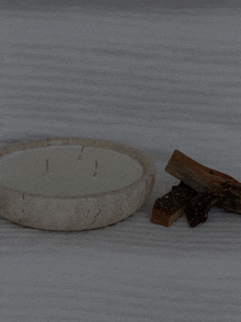 a white bowl with a candle in it sits on a table