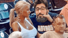 a man wearing a shirt that says astros is sitting next to a woman