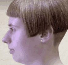 a close up of a woman 's face with a very short hairstyle and earrings .