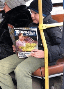 a young boy is reading a russian magazine