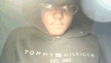 a man wearing a tommy hilfiger hoodie and sunglasses