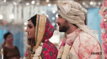 a bride and groom are standing next to each other at their wedding ceremony and looking at each other .