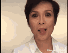 a woman with short hair is sticking her tongue out while wearing a white shirt