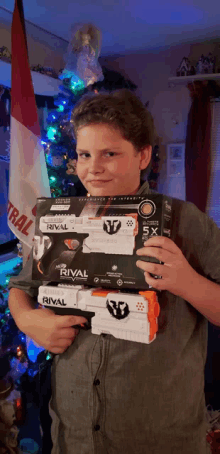 a boy holding two rival guns in front of a flag