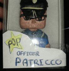 a figurine of a police officer is in a box with the name patricco written on it