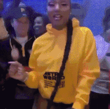 a woman in a yellow astroworld hoodie is dancing in front of a crowd