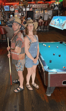 a man and a woman standing next to a pool table in a bar