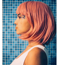 a woman wearing a pink wig and a white tank top