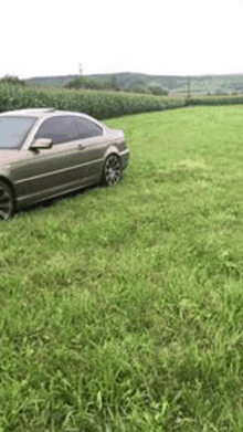 a car is parked in the middle of a field of grass .