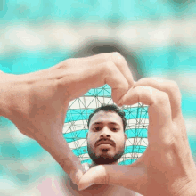 a man with a beard is making a heart shape with his fingers