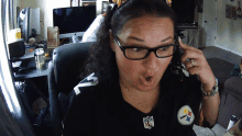 a woman wearing glasses and a pittsburgh steelers shirt looks surprised