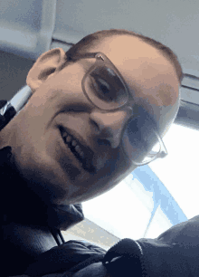 a man wearing glasses looks at the camera and smiles