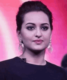 a close up of a woman 's face wearing earrings and a black top .