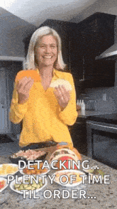 a woman in a yellow shirt is standing in a kitchen holding a piece of food and a plate of food .