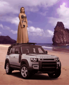 a woman in a long dress stands on top of a silver land rover defender