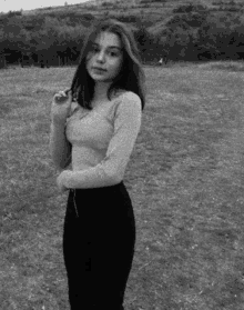 a black and white photo of a young girl standing in a field