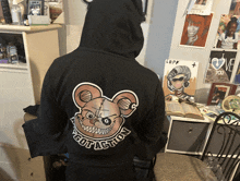 a person wearing a black hoodie with a teddy bear and the word got a shon on the back