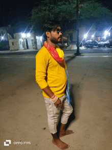 a man in a yellow sweater is standing barefoot in front of an oppo f19s