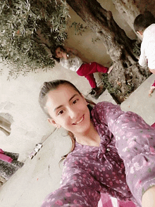 a girl in a purple floral shirt smiles for a photo