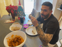 a man sitting at a table with a christmas tree in the background eating food