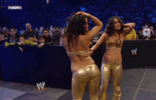 two women are dancing in front of a crowd and a wwe logo