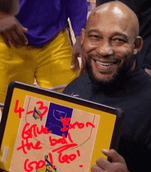 a man is smiling while holding a board with a basketball game plan on it