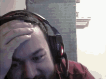 a man wearing headphones is covering his face with his hand