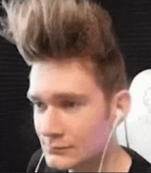 a close up of a man wearing headphones and a mohawk hairstyle .