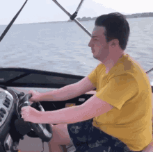 a man in a yellow t-shirt is driving a boat in the water .