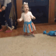 a little girl in a striped dress is dancing on the floor