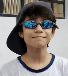 a young boy wearing a hat and sunglasses looks at the camera