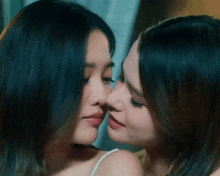 two women are kissing each other in front of a window .