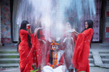 a woman in a white dress is surrounded by other women in red