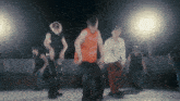 a group of young men are dancing in a dark room with a light behind them