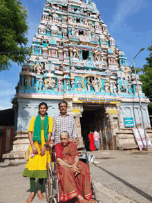 a woman in a wheelchair stands in front of a temple with a man and woman