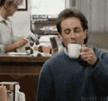 a man is drinking a cup of coffee from a mug .