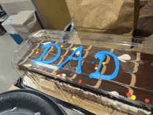 a cake in a plastic container that says dad on it